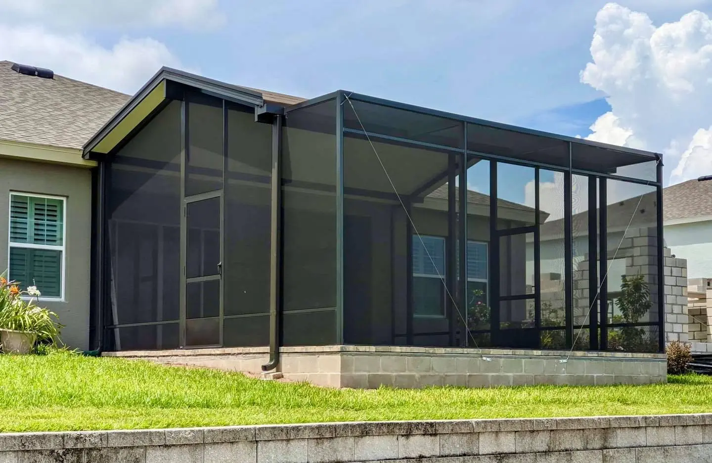 A house with a large screen porch in the middle of it.