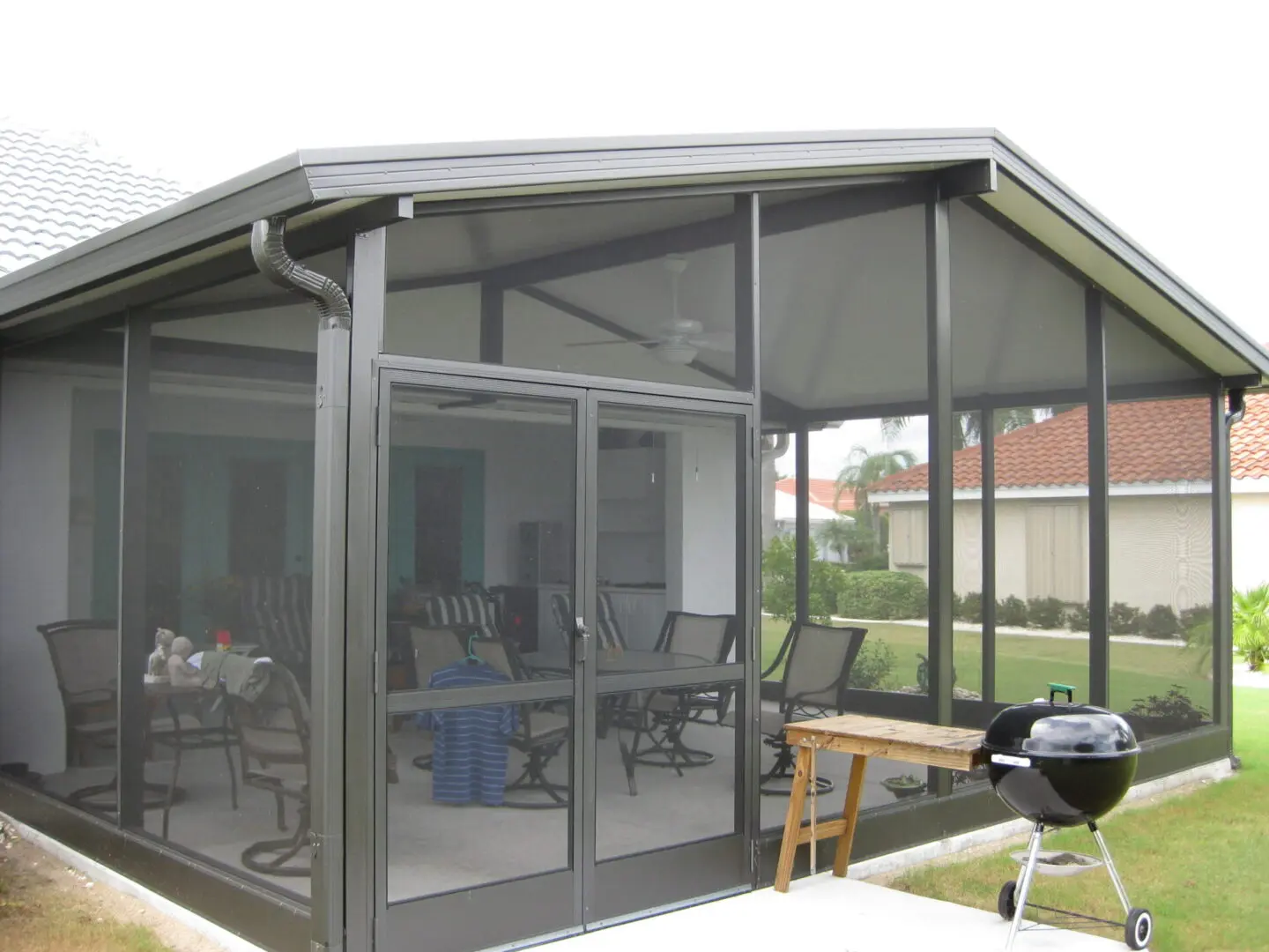 A patio enclosure with a grill and table in the background.