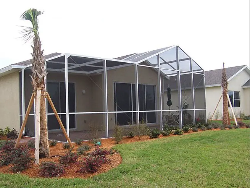 A house with a large screen porch and palm trees.