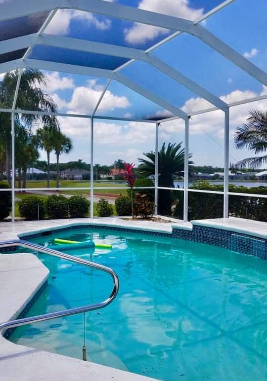 A pool with a view of the water and trees.